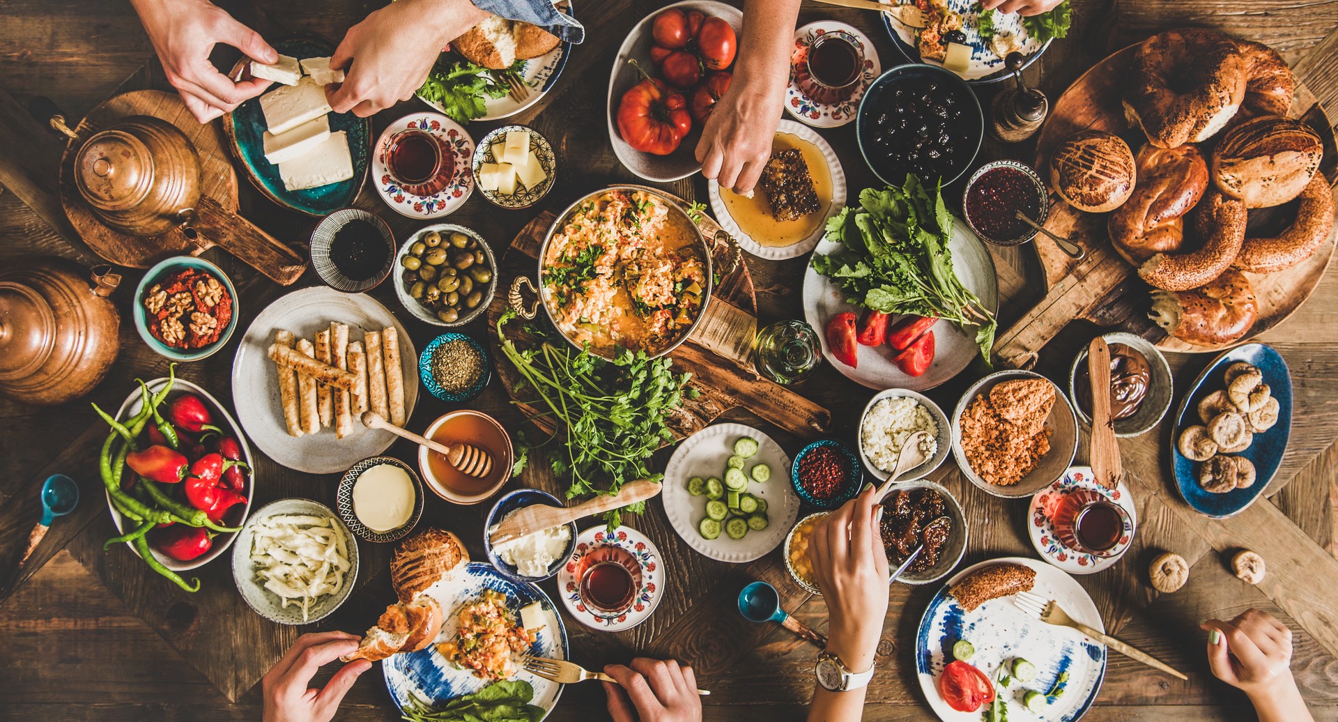 Traditional Turkish breakfast and people taking various food, wide composition