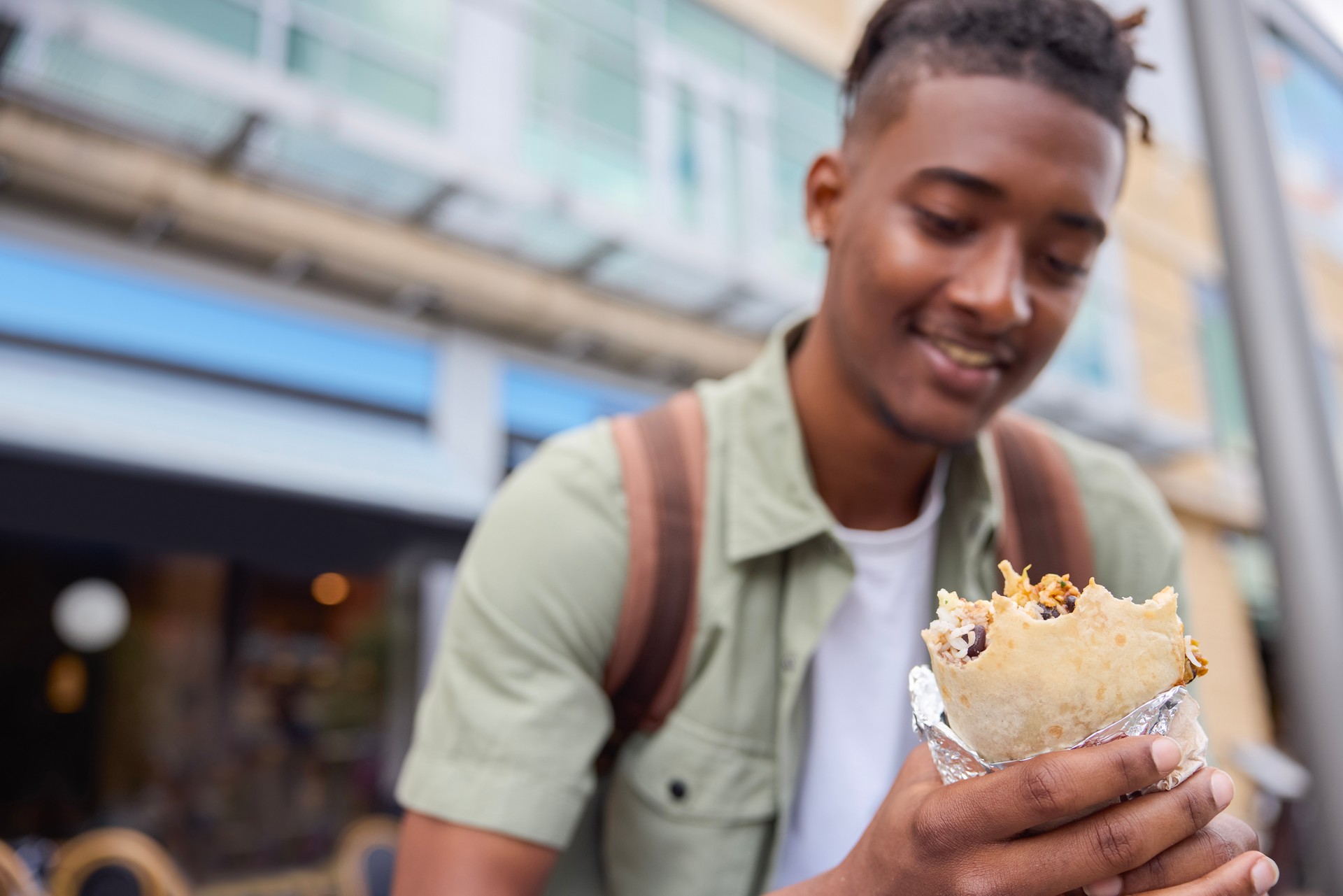 Young Man Eating Burrito At Outdoor Street Food Stall